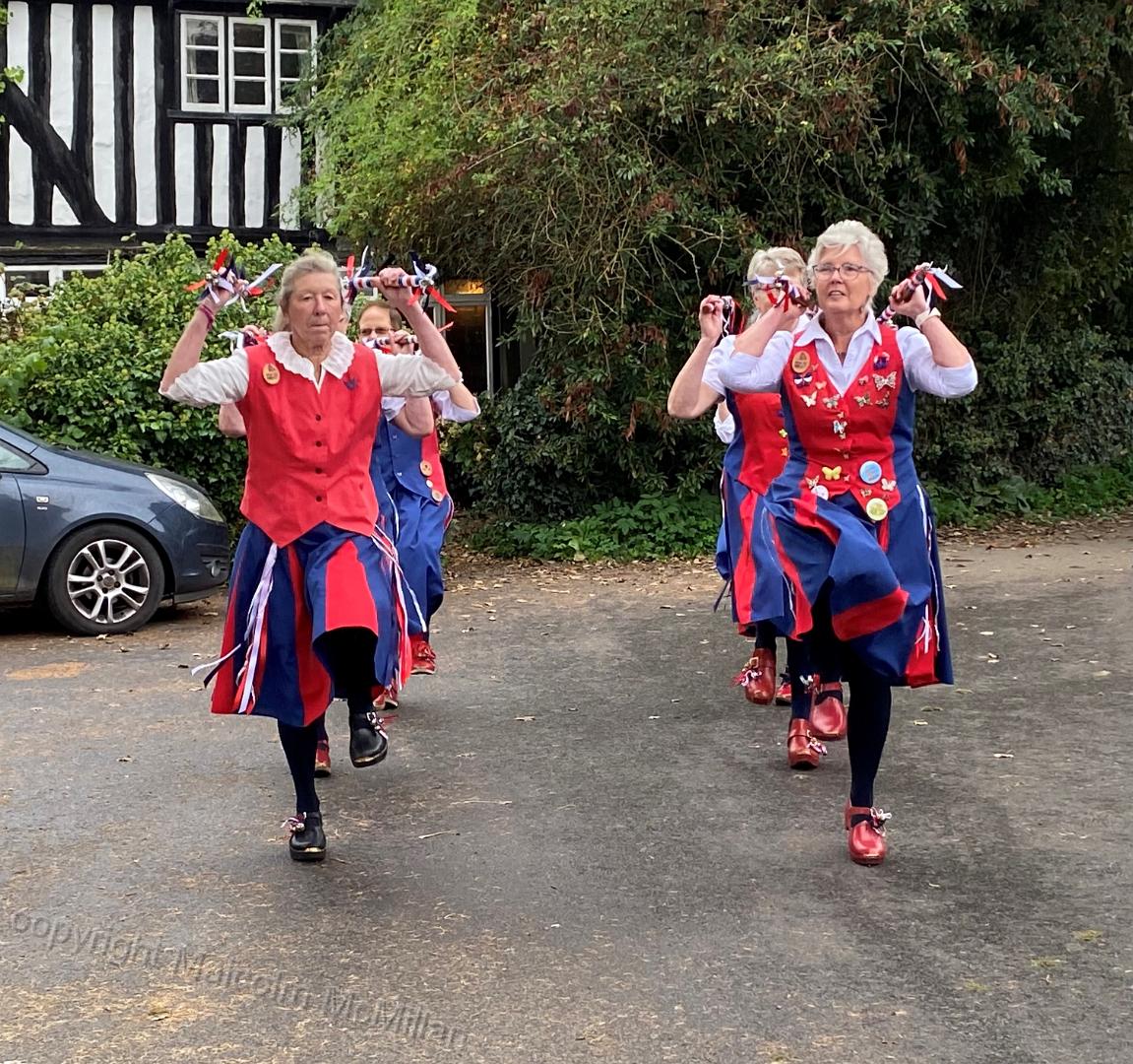 two rows of 4 dancers with sticks at shoulder height